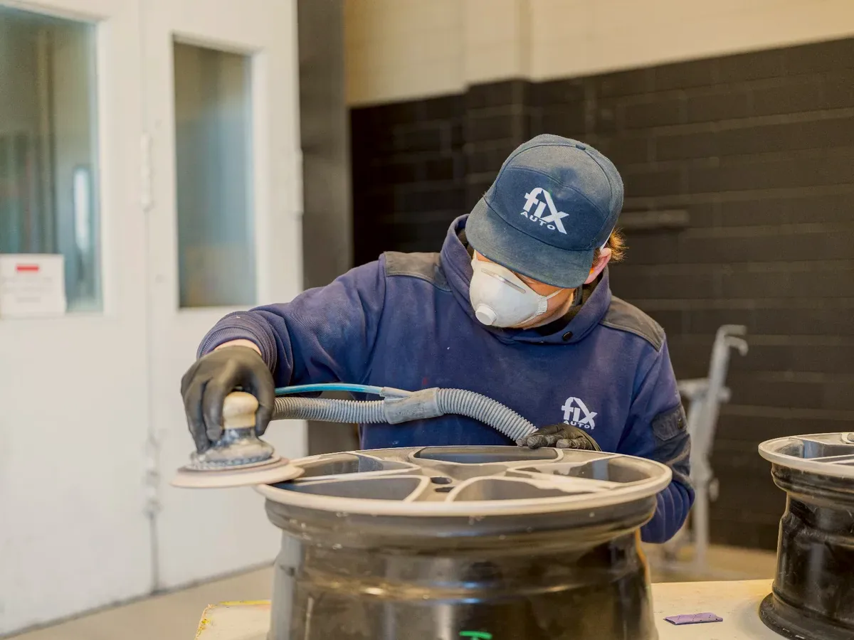 Technician refinishing an alloy wheel at Fix Auto Hamilton South