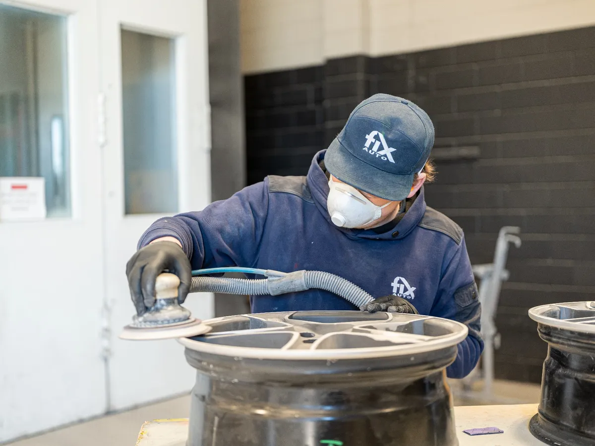 Technician refinishing an alloy wheel at Fix Auto Hamilton South
