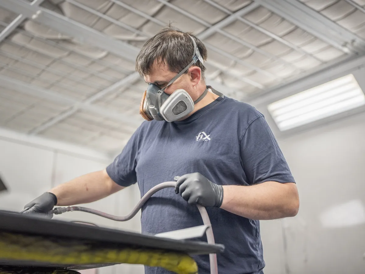 A painter in a respirator at work in the spray booth at Fix Auto Palmerston North CBD